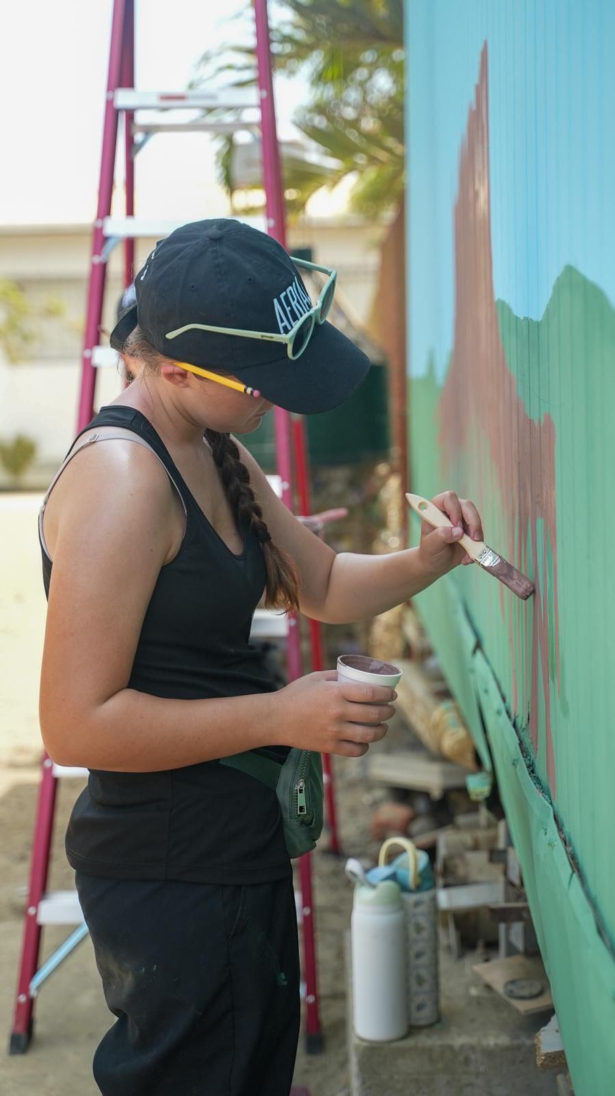 A volunteer painting a mural as part of the build-out