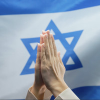 Praying hands over the flag of Israel